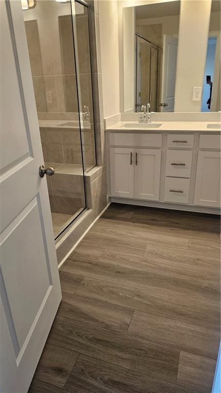 bathroom featuring vanity, wood-type flooring, and a shower with shower door