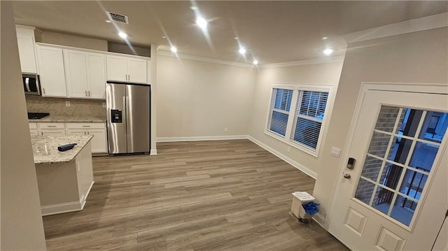 kitchen featuring decorative backsplash, light stone counters, stainless steel appliances, crown molding, and white cabinets