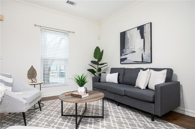 living room featuring baseboards, visible vents, crown molding, and wood finished floors