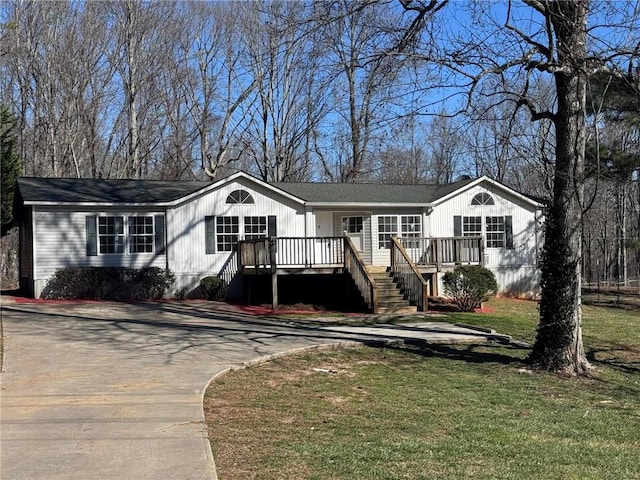 ranch-style house with driveway, a wooden deck, and a front yard