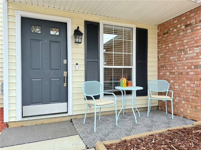 property entrance featuring brick siding and covered porch