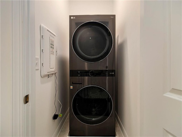 laundry room with electric panel and stacked washing maching and dryer