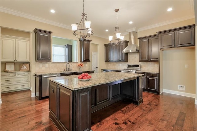 kitchen featuring sink, stainless steel appliances, a center island, cream cabinets, and wall chimney exhaust hood