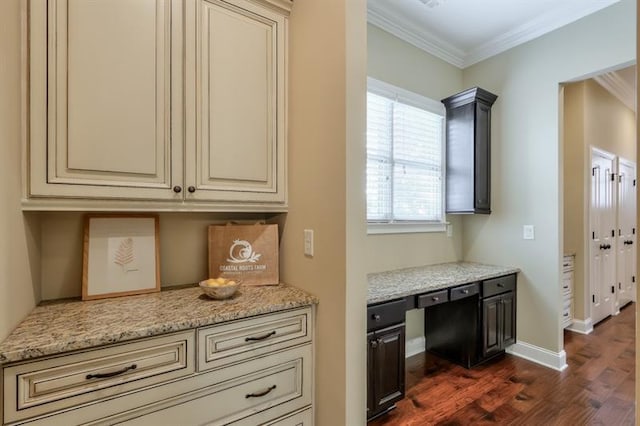 kitchen with light stone counters, crown molding, dark wood-type flooring, and cream cabinetry