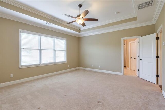 carpeted empty room featuring crown molding, a tray ceiling, and ceiling fan