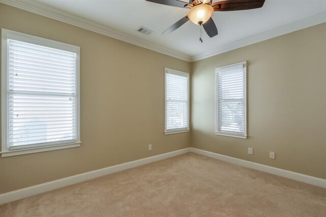 unfurnished room featuring ornamental molding, plenty of natural light, light colored carpet, and ceiling fan