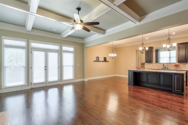 unfurnished living room with coffered ceiling, dark hardwood / wood-style floors, ceiling fan with notable chandelier, and beamed ceiling