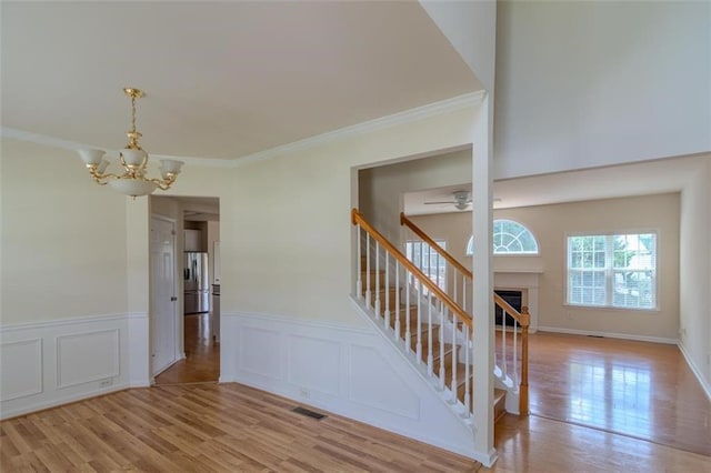 851 Roget Ct, Lawrenceville, GA 30045 - stairway with a chandelier, wood finished floors, ornamental molding, a wainscoted wall, and ceiling fan