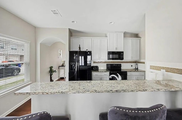 5076 Longview Walk, Decatur, GA 30035 - kitchen featuring arched walkways, visible vents, backsplash, light stone countertops, and black appliances