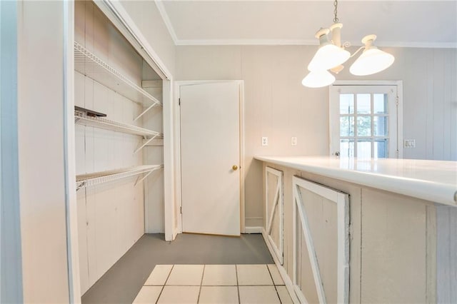 kitchen with crown molding, wooden walls, pendant lighting, and a notable chandelier