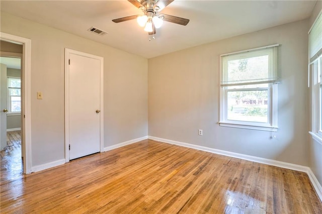 empty room with light hardwood / wood-style flooring, a wealth of natural light, and ceiling fan