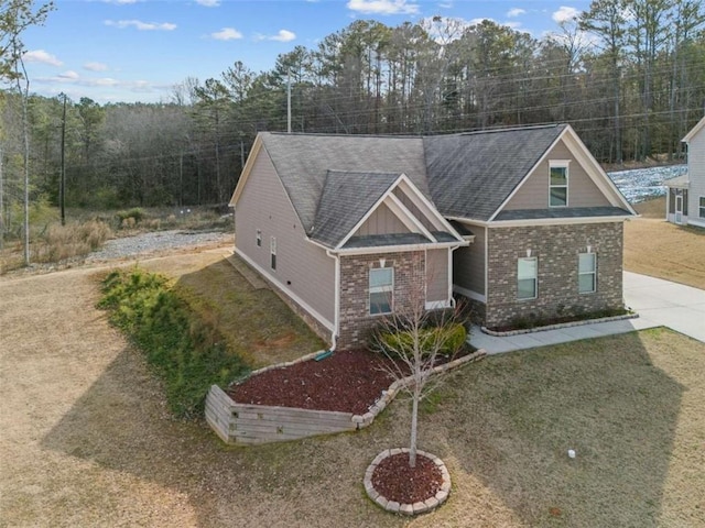 view of front facade with board and batten siding, brick siding, and driveway