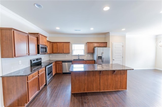 kitchen featuring stainless steel appliances, dark wood-type flooring, a kitchen island, a sink, and ornamental molding