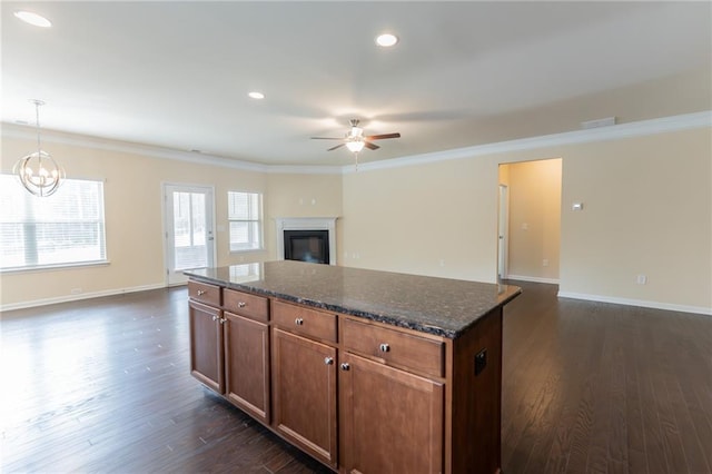 kitchen with dark wood-type flooring, open floor plan, crown molding, and a kitchen island