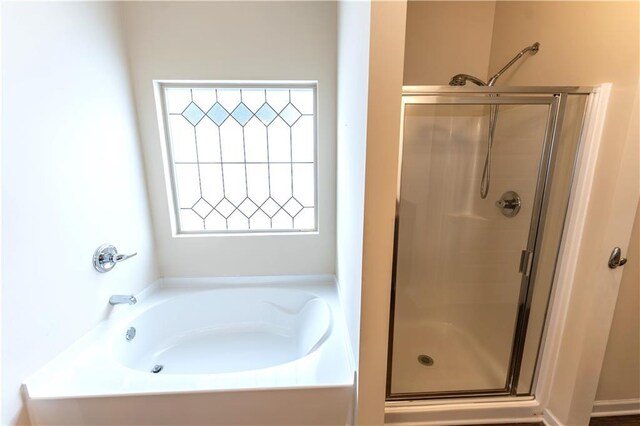 bathroom with a stall shower and a garden tub