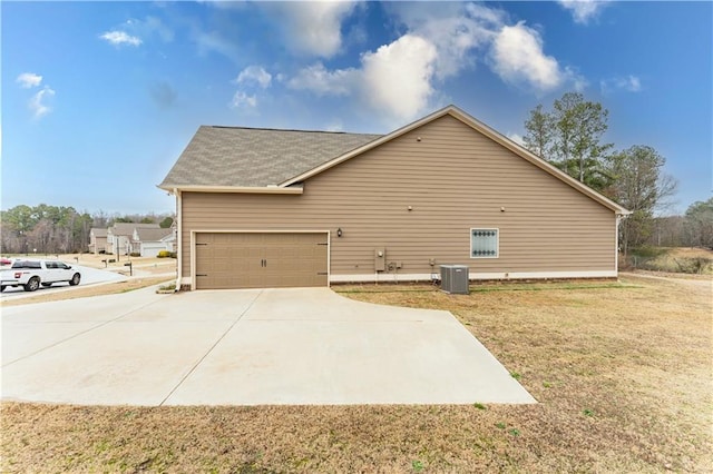 view of side of property featuring a garage, driveway, a yard, and cooling unit