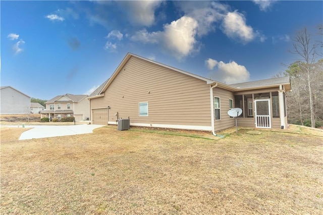 view of side of property with a yard, central air condition unit, a sunroom, a garage, and driveway