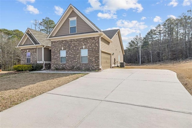 view of front of home with a garage, concrete driveway, brick siding, and central air condition unit