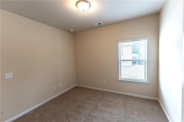 empty room with carpet, visible vents, and baseboards