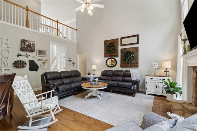 2713 Misty Rock Cv, Dacula, GA 30019 - living room featuring a high ceiling, stairs, a fireplace with raised hearth, a ceiling fan, and wood finished floors