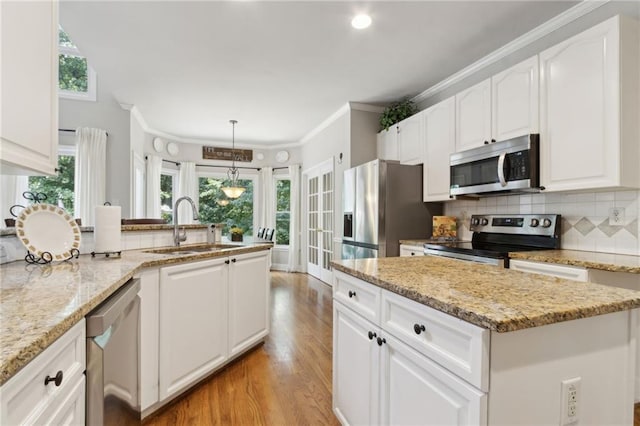 2713 Misty Rock Cv, Dacula, GA 30019 - kitchen featuring stainless steel appliances, light wood-style flooring, a peninsula, plenty of natural light, and ornamental molding