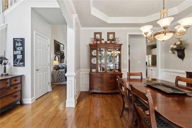 2713 Misty Rock Cv, Dacula, GA 30019 - dining room with light wood-style flooring, a raised ceiling, ornamental molding, wainscoting, and ornate columns