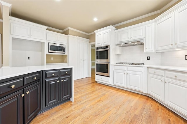 kitchen featuring light wood-type flooring, backsplash, stainless steel appliances, crown molding, and white cabinets