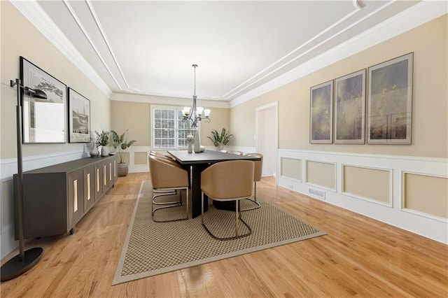 dining room featuring light wood-type flooring, ornamental molding, and a chandelier