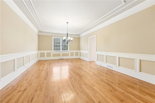 unfurnished dining area with light hardwood / wood-style flooring, crown molding, and an inviting chandelier