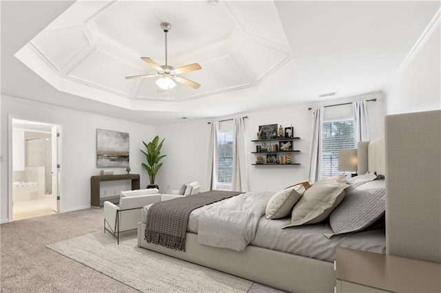 carpeted bedroom with ceiling fan, a raised ceiling, ensuite bathroom, and multiple windows