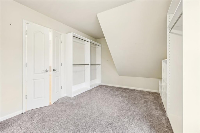 walk in closet with light colored carpet and lofted ceiling