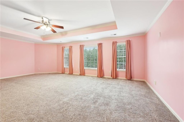 carpeted spare room with a tray ceiling, ceiling fan, and ornamental molding