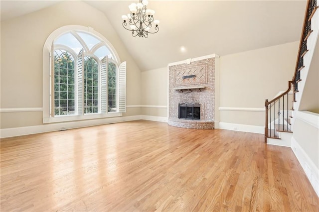 unfurnished living room with a fireplace, light hardwood / wood-style flooring, lofted ceiling, and a notable chandelier