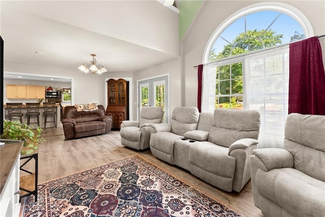 living room featuring a high ceiling, a wealth of natural light, light hardwood / wood-style flooring, and a notable chandelier