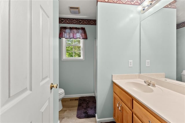 bathroom featuring toilet, wood-type flooring, and vanity