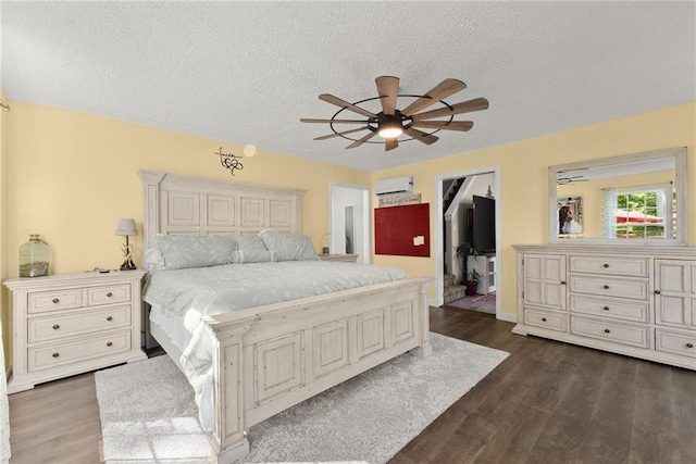 bedroom featuring ceiling fan, a textured ceiling, dark hardwood / wood-style flooring, and a wall mounted air conditioner