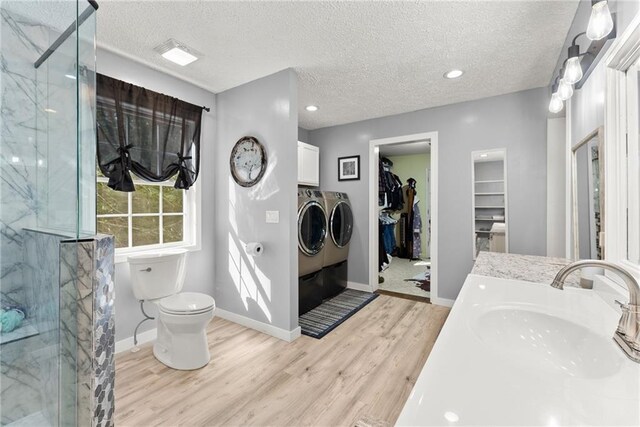 bathroom featuring separate washer and dryer, a textured ceiling, wood-type flooring, a shower with door, and vanity