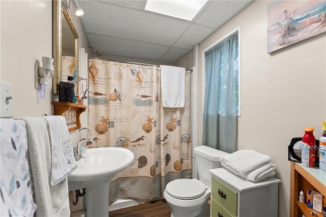 bathroom featuring toilet, a drop ceiling, and walk in shower