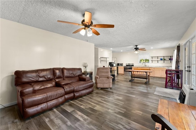 living room featuring ceiling fan, a textured ceiling, and dark hardwood / wood-style flooring