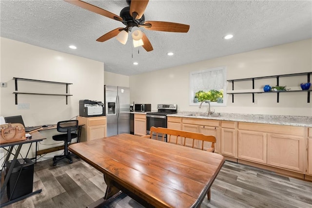 kitchen featuring a textured ceiling, appliances with stainless steel finishes, light brown cabinetry, sink, and ceiling fan