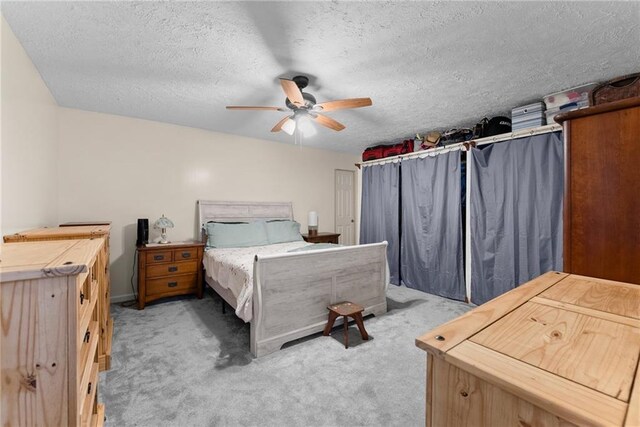 carpeted bedroom with ceiling fan and a textured ceiling