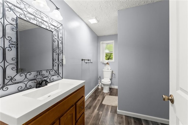 bathroom with toilet, vanity, a textured ceiling, and hardwood / wood-style floors