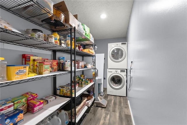 washroom featuring a textured ceiling, stacked washer / dryer, and wood-type flooring