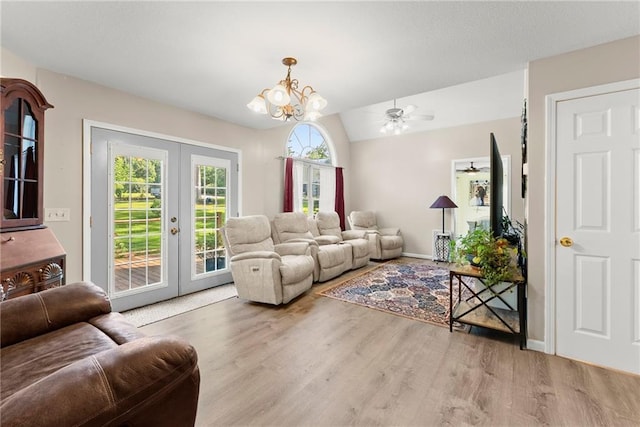 living room featuring light wood-type flooring, french doors, ceiling fan with notable chandelier, and lofted ceiling