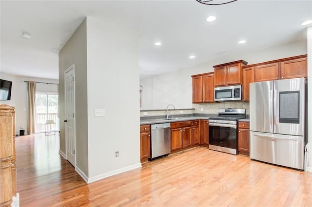 3622 Utoy Dr, South Fulton, GA 30331 - kitchen with appliances with stainless steel finishes, brown cabinetry, light wood-style flooring, tasteful backsplash, and a sink
