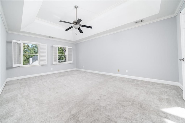 unfurnished room featuring light carpet, crown molding, ceiling fan, and a raised ceiling