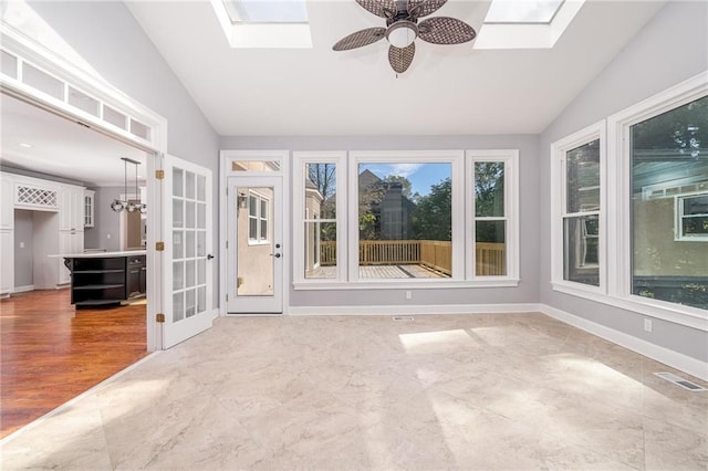 unfurnished sunroom with vaulted ceiling with skylight and ceiling fan with notable chandelier