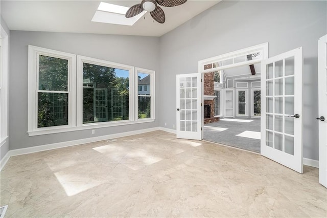 interior space featuring vaulted ceiling with skylight, french doors, and ceiling fan