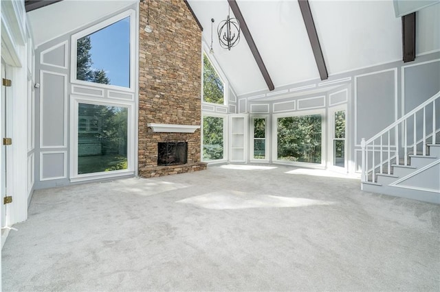 unfurnished living room featuring beamed ceiling, carpet, a fireplace, and high vaulted ceiling