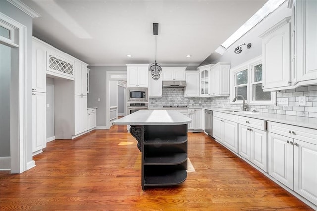 kitchen with white cabinets, a kitchen island, stainless steel appliances, sink, and decorative light fixtures